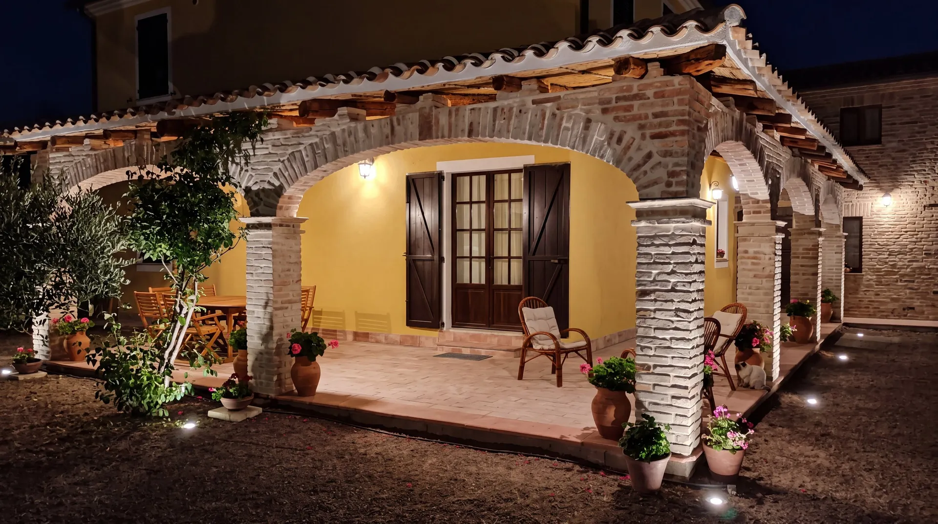 Veranda in stile campidanese con archi in mattoni sardi illuminata la sera, a Santa Margherita di Pula